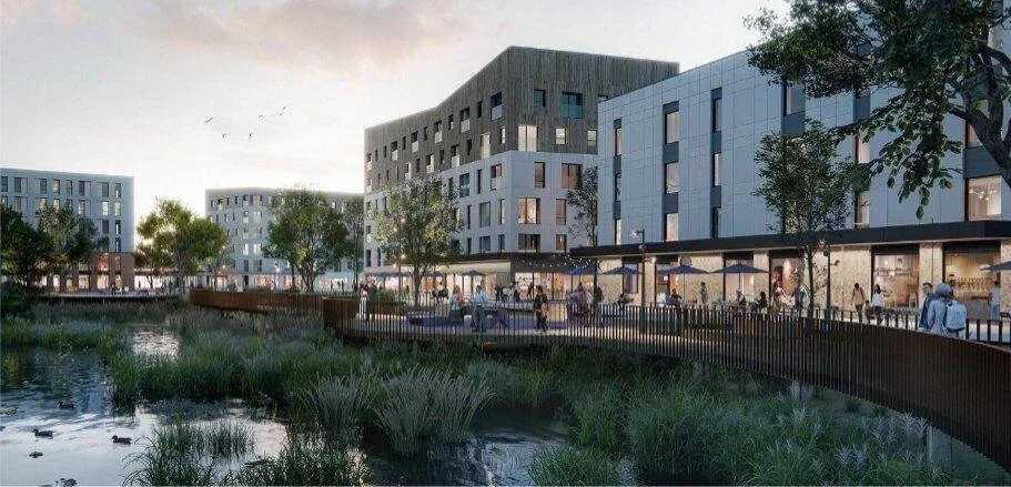 Modern multi-story buildings with ground-floor shops and outdoor seating, overlooking a pond with ducks and surrounding greenery, during dusk.