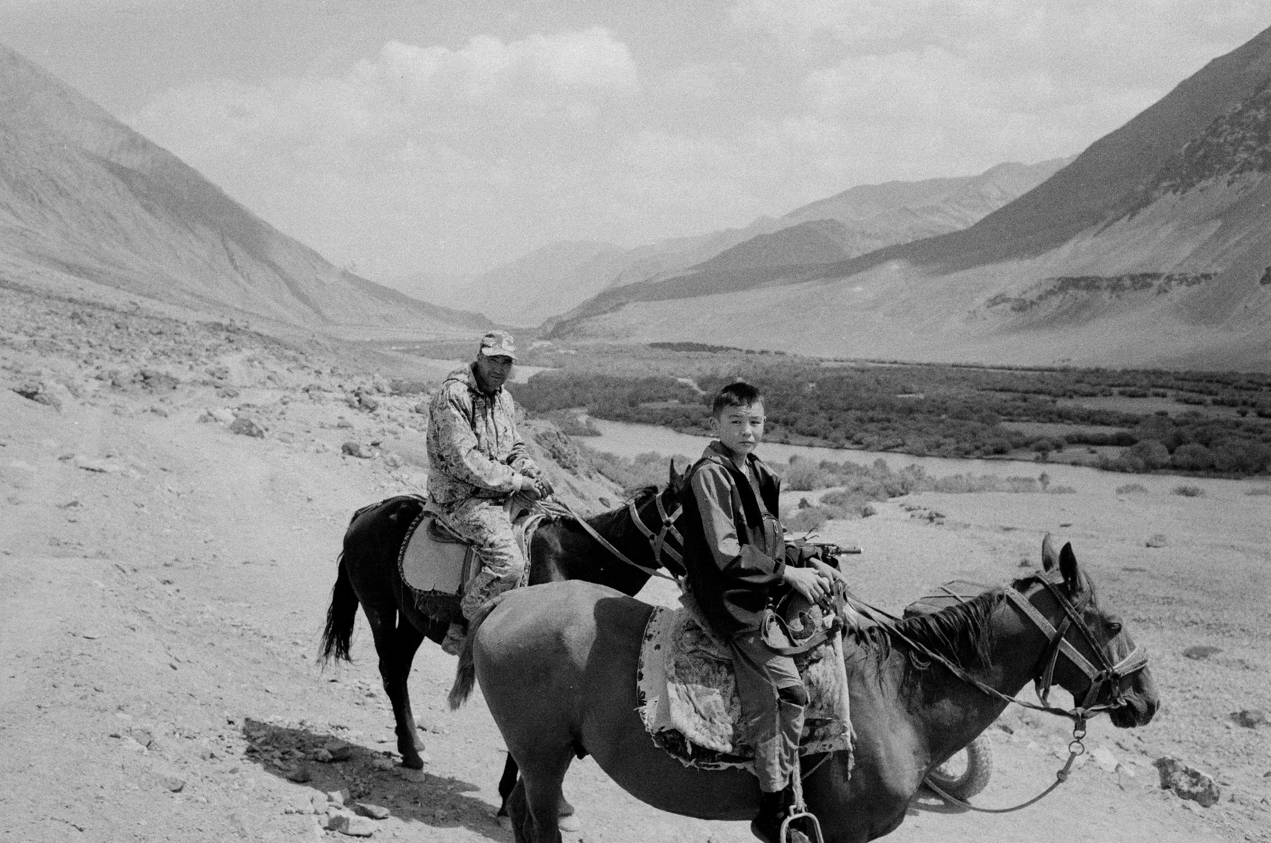 Deux hommes en tenue militaire sur des chevaux dans un paysage montagneux.
