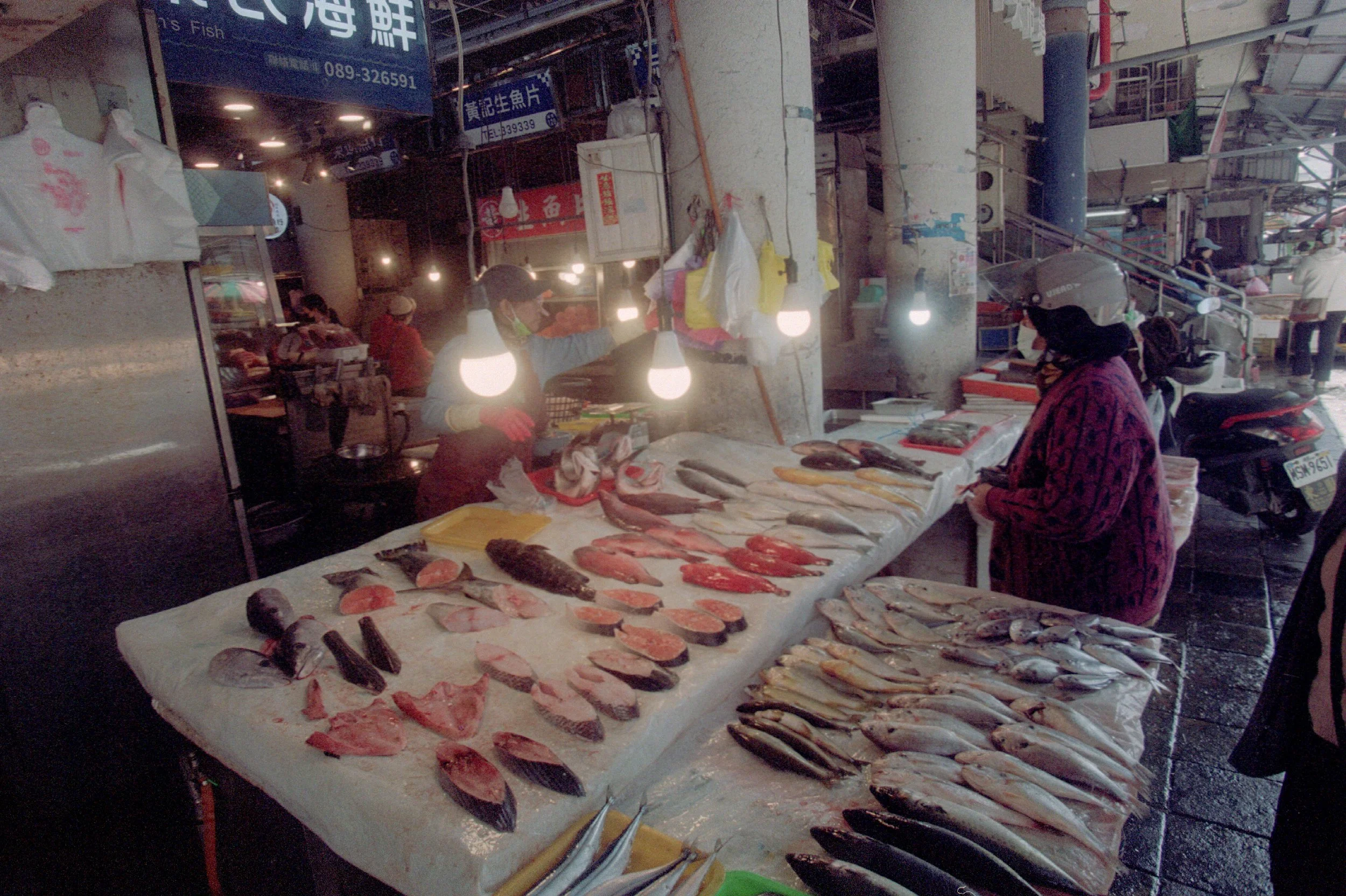 Un étal de poissons frais dans un marché de nuit avec des clients et des vendeurs