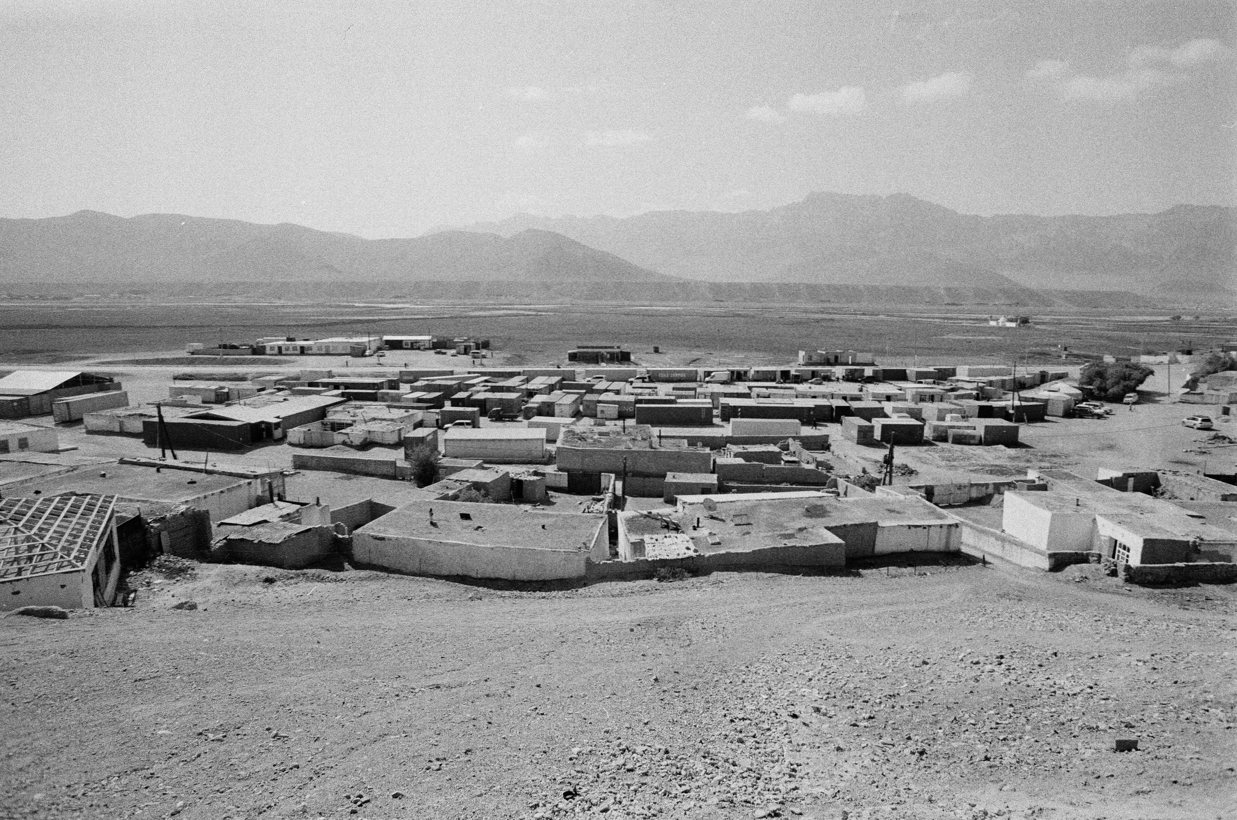 Vue sur un campement de tentes et de véhicules dans un désert avec des montagnes à l'arrière-plan.