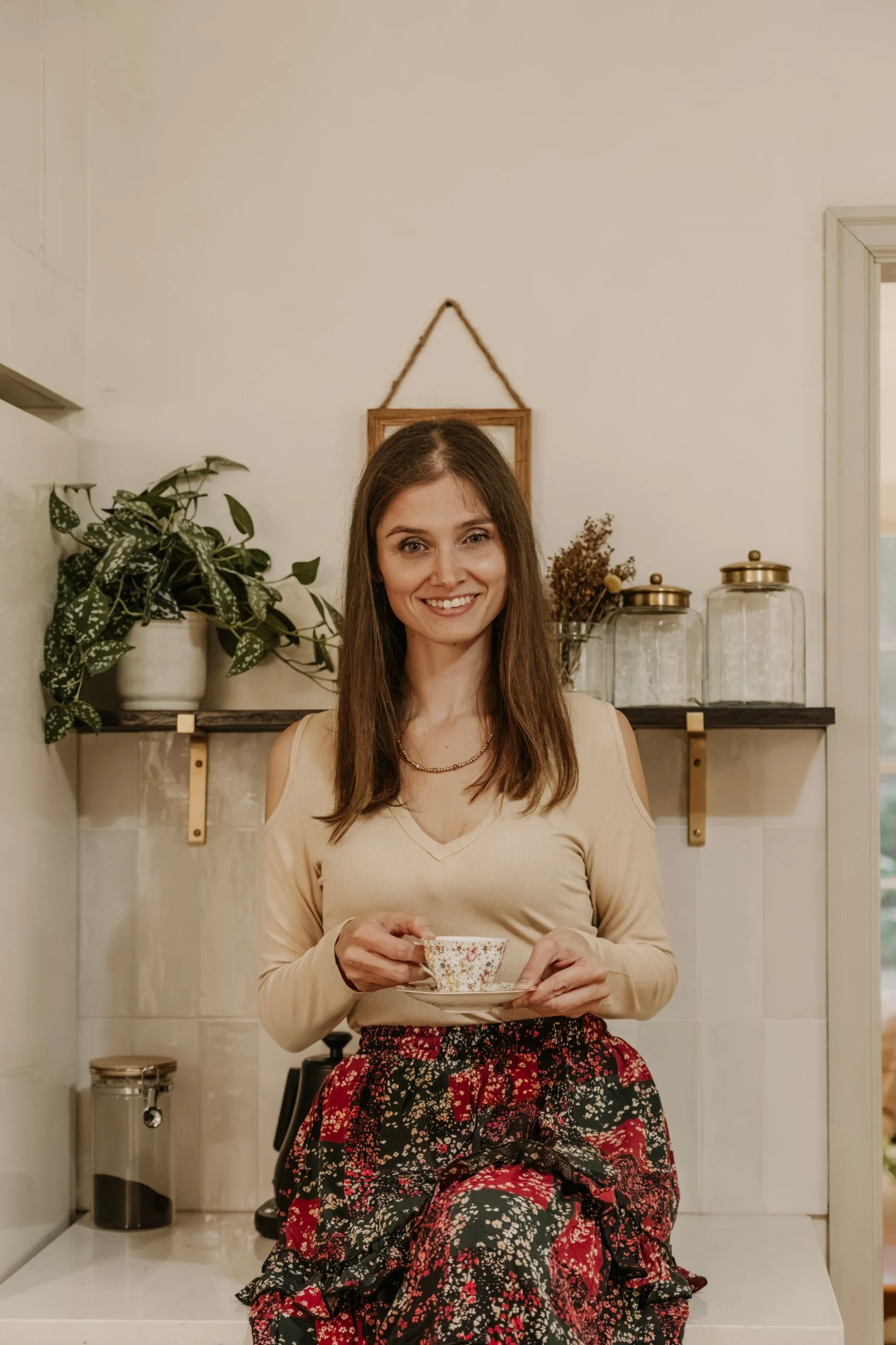 Cassandra sitting on a kitchen counter with a cup of tea in a cozy home