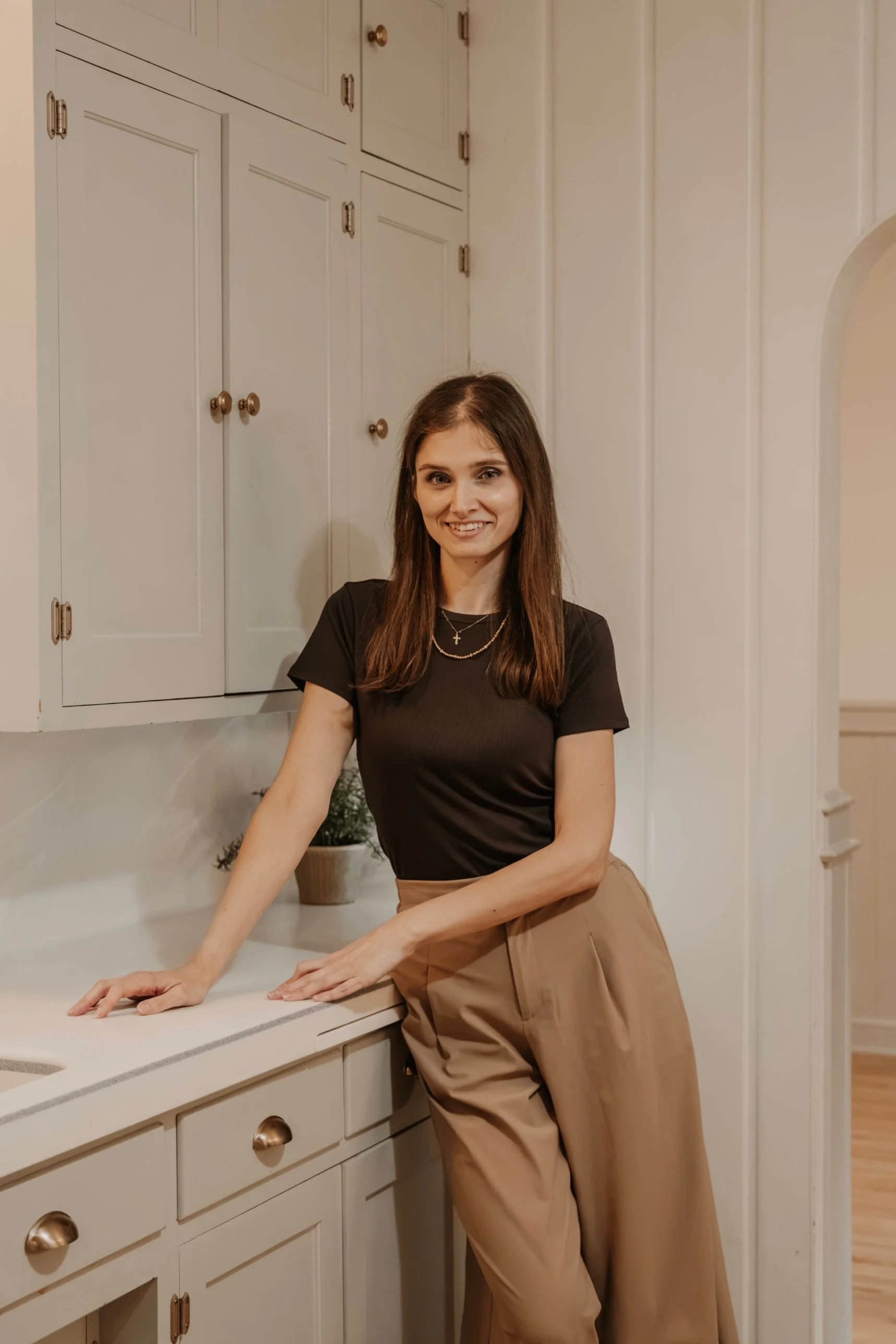 Cassandra leaning casually against a kitchen counter in a cozy home