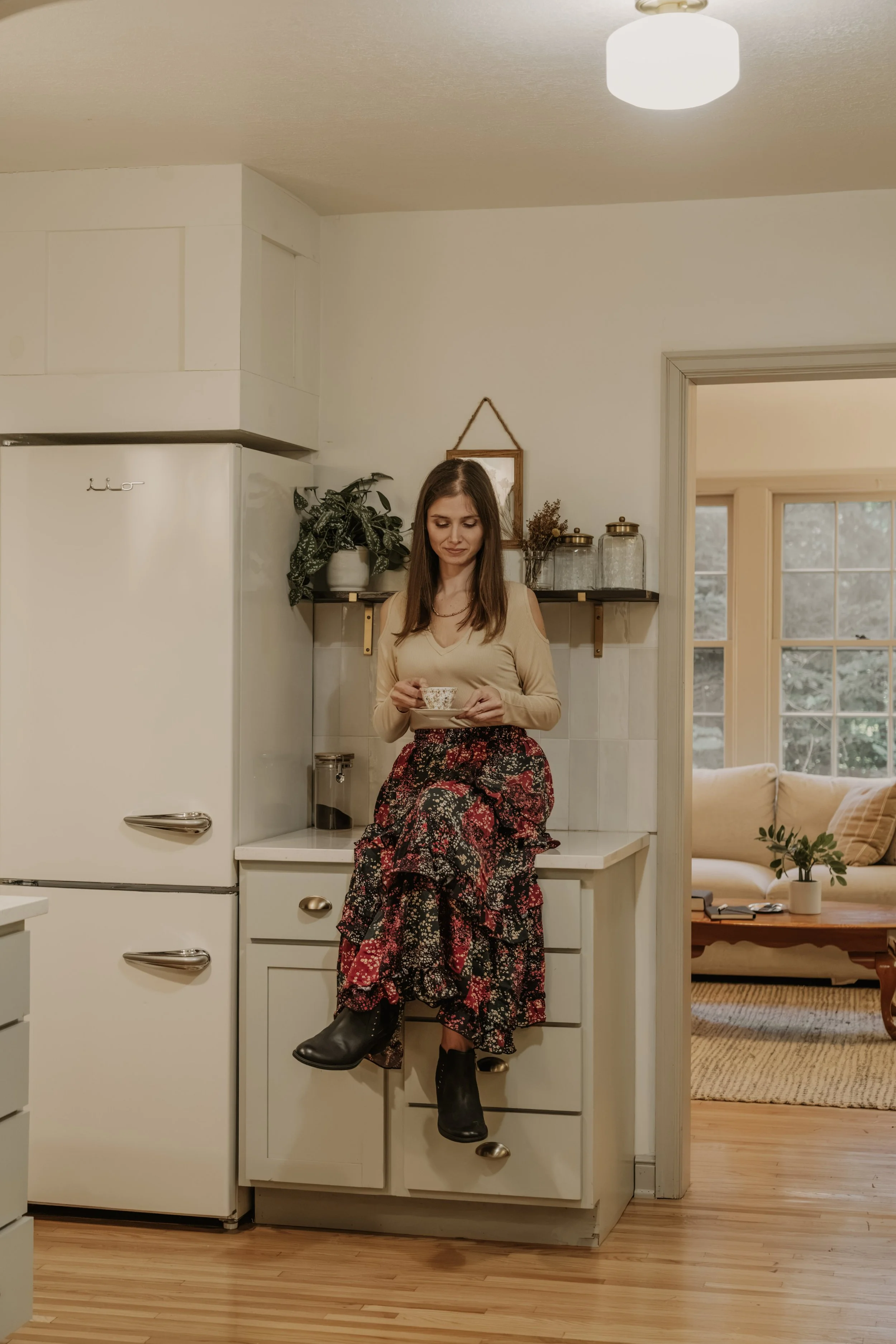 Cassandra sitting on a kitchen counter with a cup of tea in a cozy home