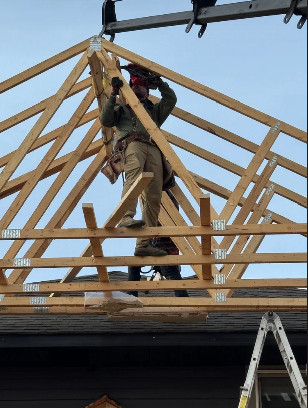 Wooden framing for a building under construction against a clear blue sky.