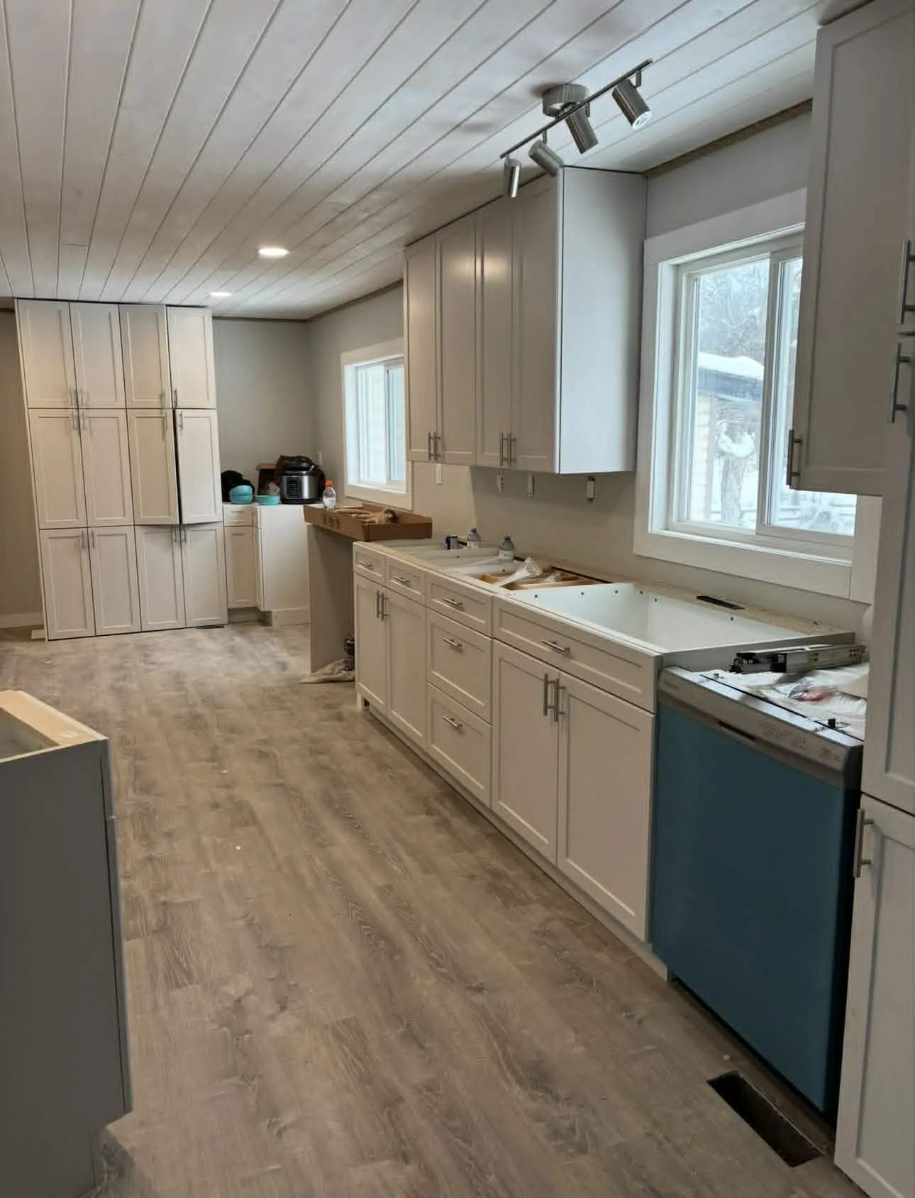 Modern kitchen with wooden cabinets, black countertops, a stainless steel range hood, potted cactus, wall clock, and decorative ceramics.