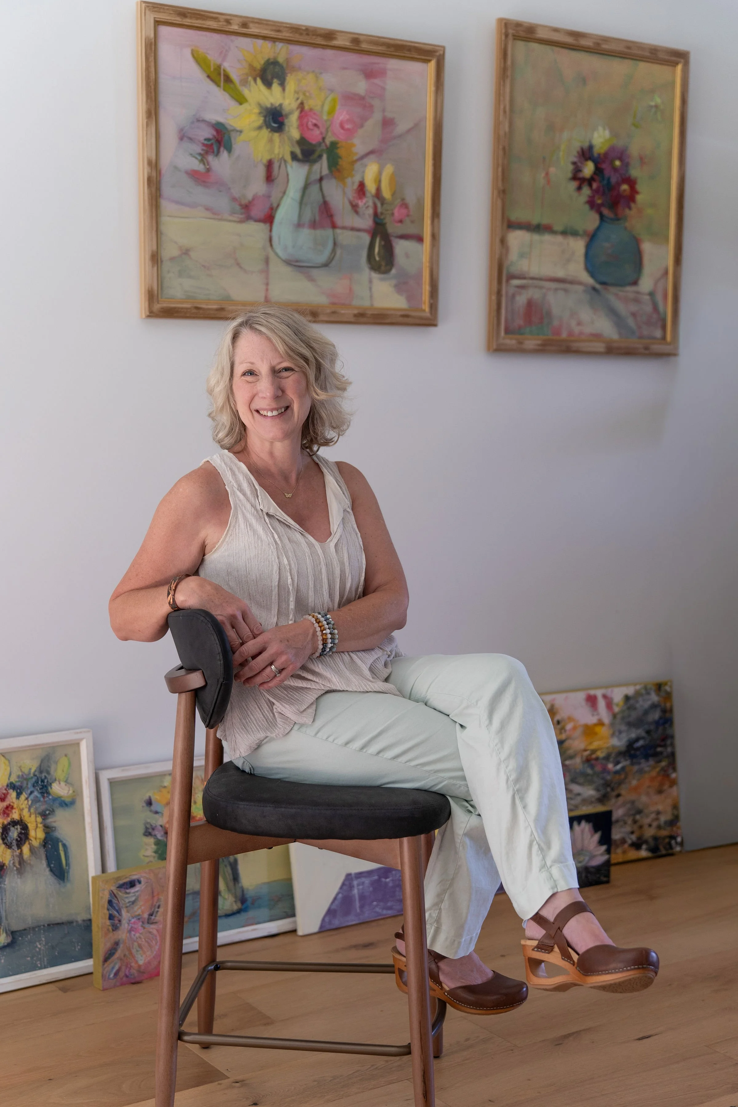 Lisa Wagner sitting with her various intuitive acrylic floral works