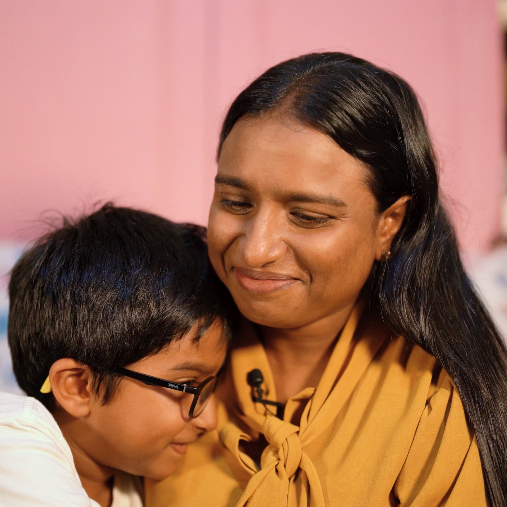 A woman and a young boy sharing a tender moment, with the woman smiling softly as the boy rests his head on her shoulder.