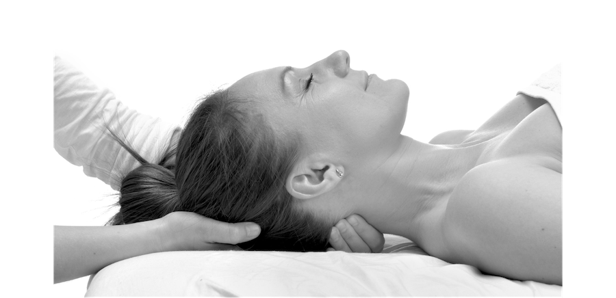 Regenerate alt text copyIconcrossIconBlue A woman lies on her back with eyes closed, receiving a relaxing head and neck craniosacral treatment.