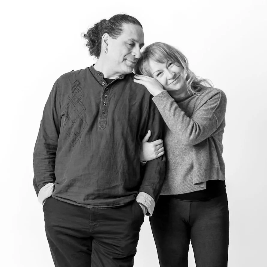 Regenerate alt text copyIconcrossIconBlue A smiling woman leans her head on a mans shoulder; they stand arm in arm against a plain white background.