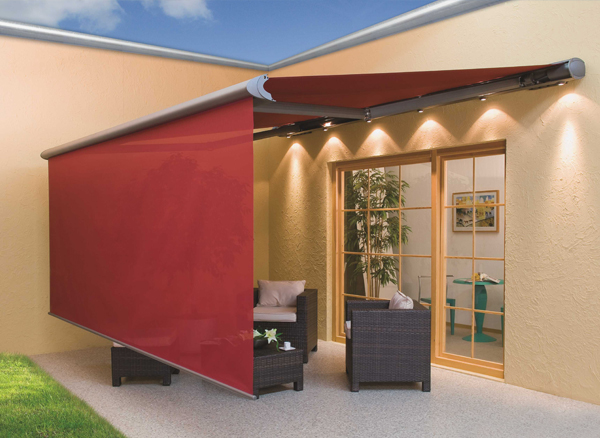 Outdoor patio with a red retractable awning, wicker furniture with cushions, and a view into a room with artwork and a potted plant.