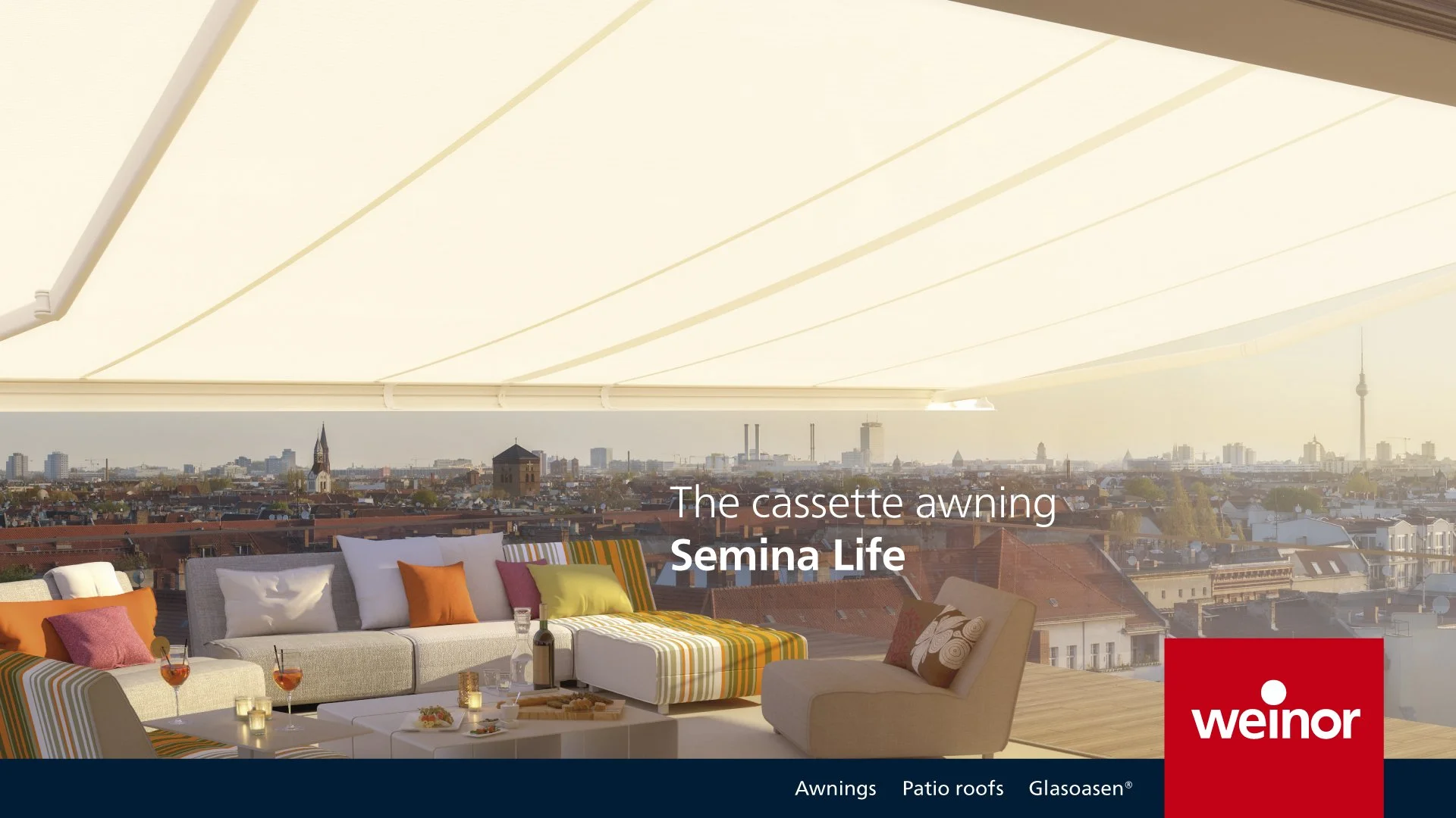 Outdoor rooftop lounge with colorful seating and a city view with the skyline in the background, under a large beige cassette awning.