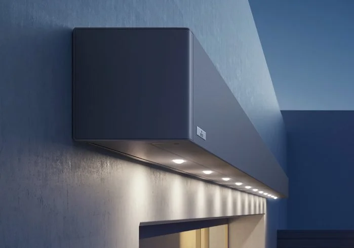 Close-up of a dark blue outdoor soffit with built-in recessed lighting and a small electrical outlet, mounted on a gray textured wall.
