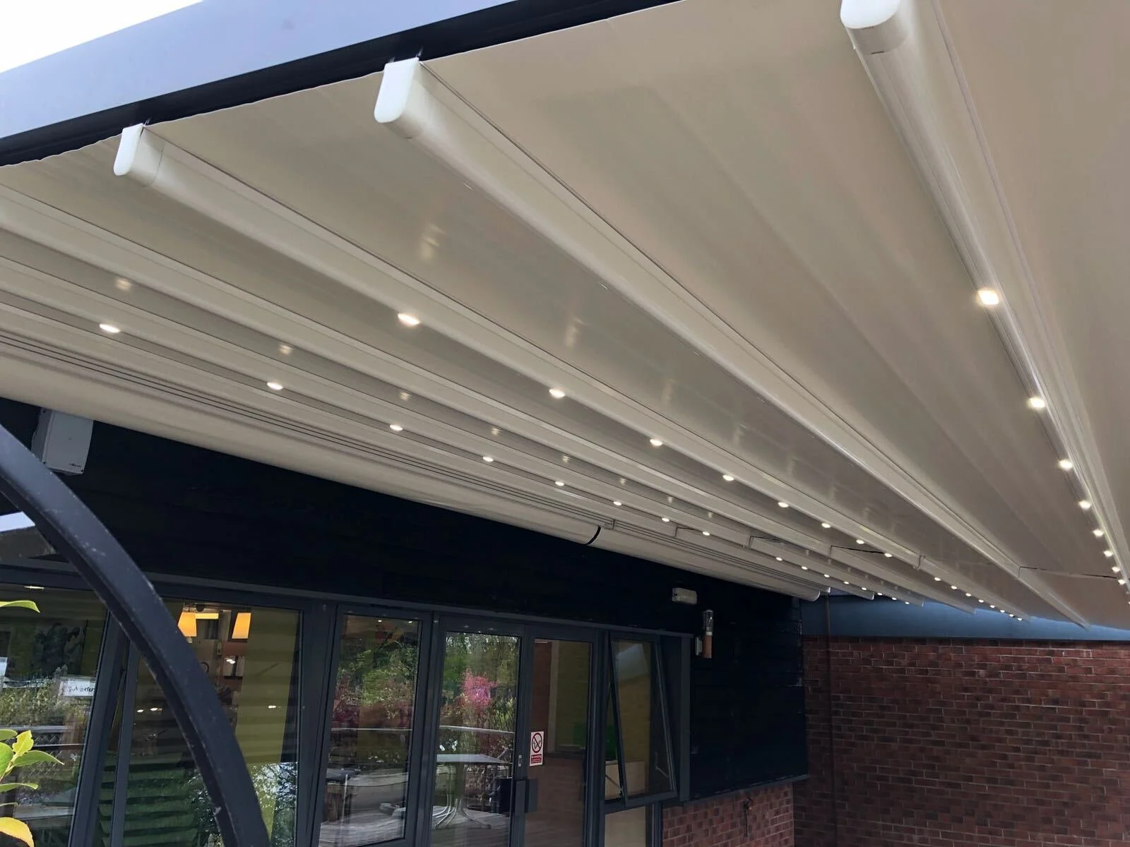 Retractable white awning with built-in lighting extending over a building's entrance.