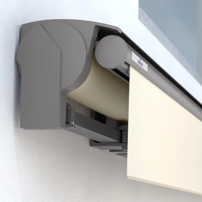 A ceiling-mounted projector with a filter or lens cover, projecting onto a beige surface.