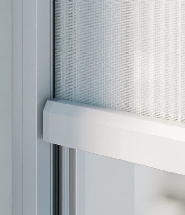 Close-up of a white metal and glass door or window frame with a perforated metal screen or panel.