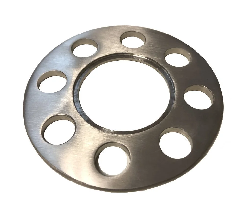 A metallic circular object with a large central hole and eight smaller holes evenly spaced around it.