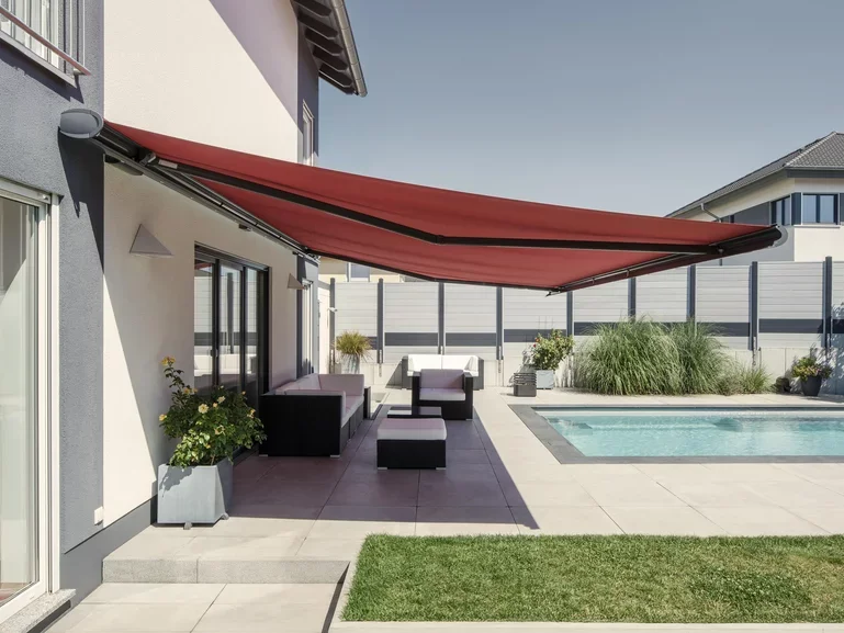 Outdoor backyard with a pool, patio furniture, potted plants, and a retractable red awning.