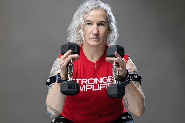 Seli Strength client performing a squat with 7.5-pound dumbbells and BFR cuffs