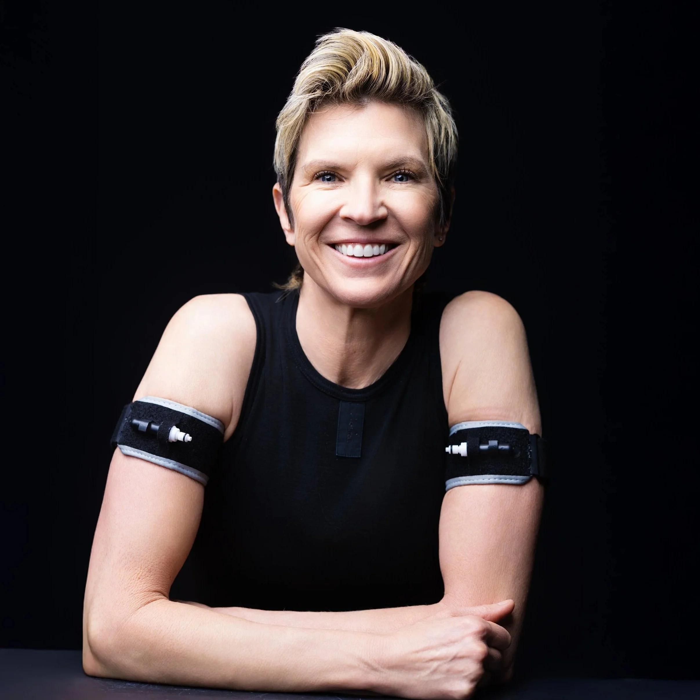 Ashley Selman smiling with BFR bands on her upper arms — Seli Strength blood flow restriction training