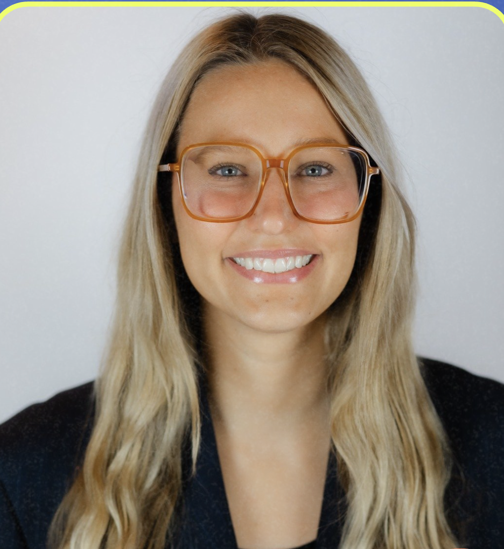 A headshot of a woman with square glasses and long, blonde hair.