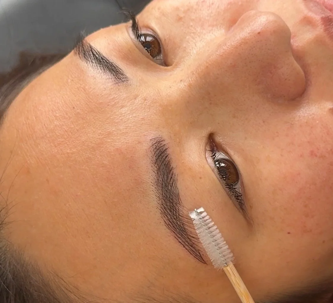 Person lying down with an eyebrow brush grooming their eyebrows.