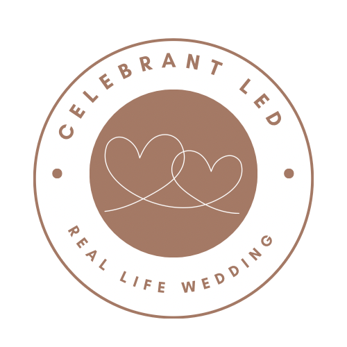 A circular logo with a brown background and white text that reads 'Celebrant Led' at the top and 'Real Life Wedding' at the bottom, featuring two interconnected hearts in the center.