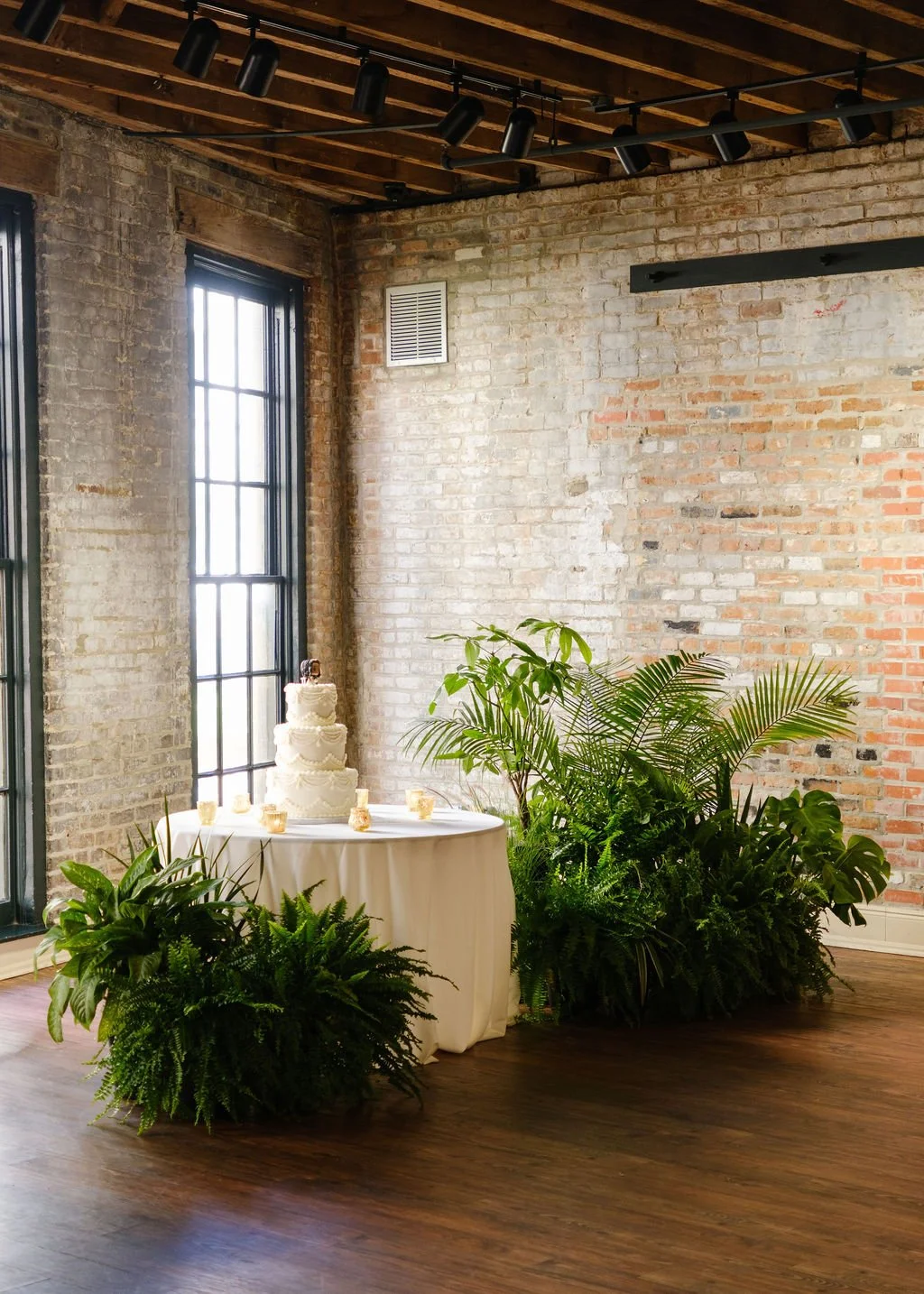 wedding-cake-display-with-lush-plants-modern-reception.jpg