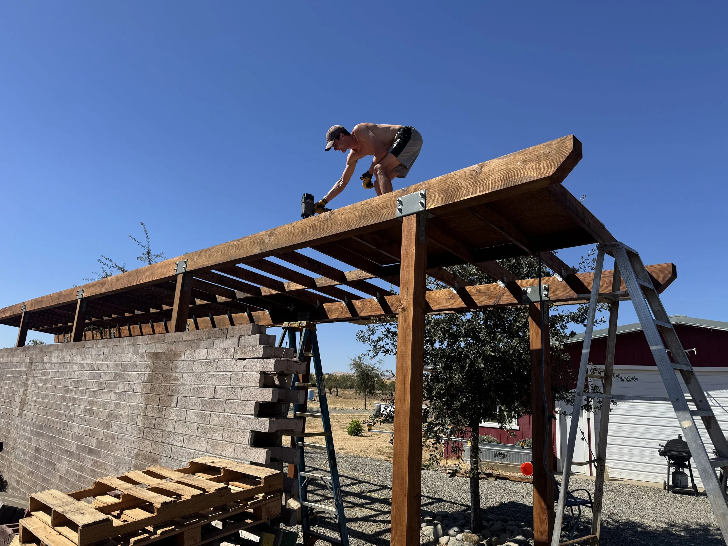 Young man on future roof of pole barn with nail gun