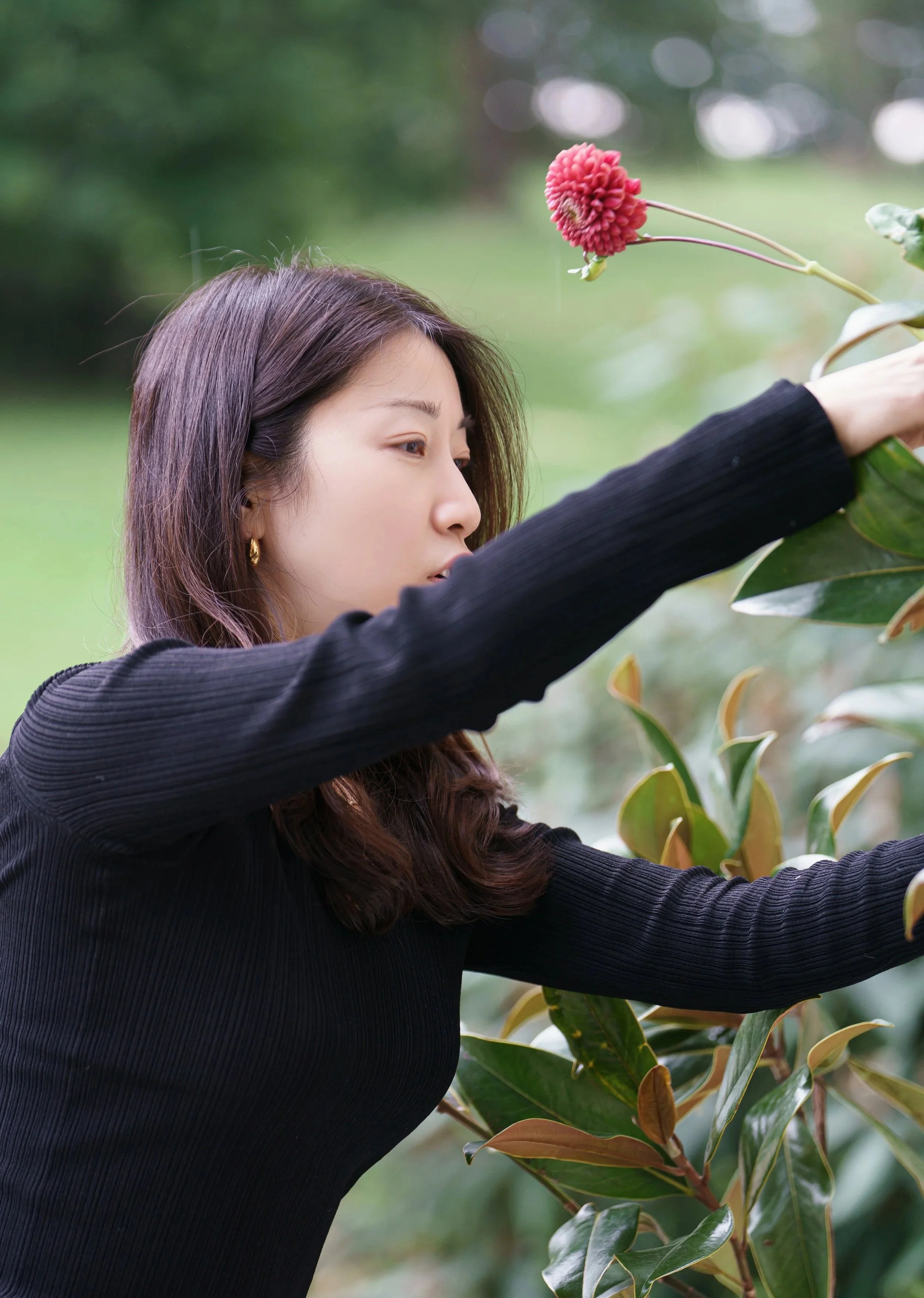 Une femme qui vérifie une plante dans un jardin ou une parc lors de la journée.