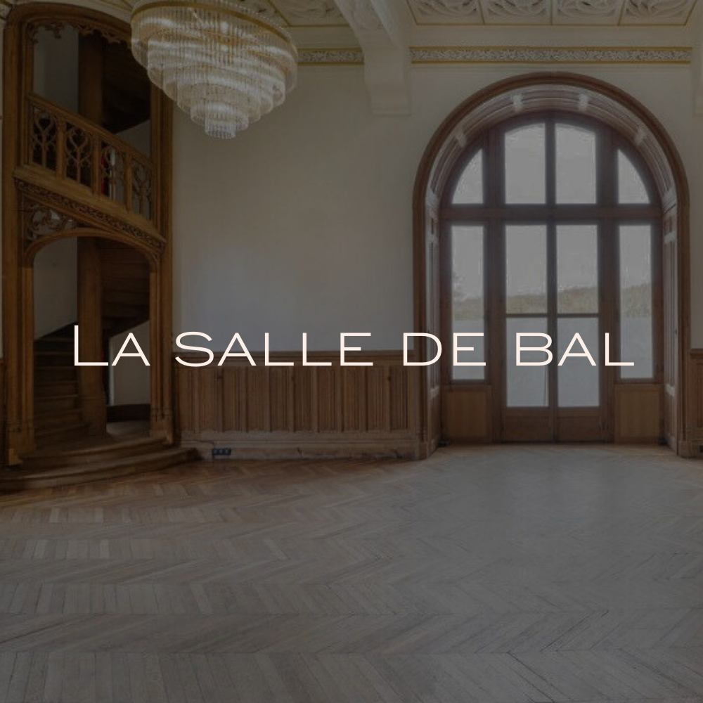 Une salle de bal décorée pour un mariage avec une table élégante, des fleurs colorées et des chandeliers, avec un couple en tenue de mariage posant à côté.