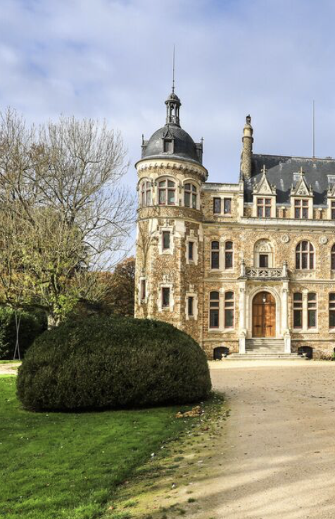 Château historique avec tourelle, fenêtres élégantes et paysage verdoyant.