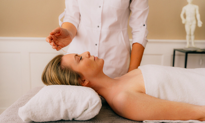 Image of woman in a serene clinic treatment room receiving acupuncture and seeming content and comfortable and relaxed