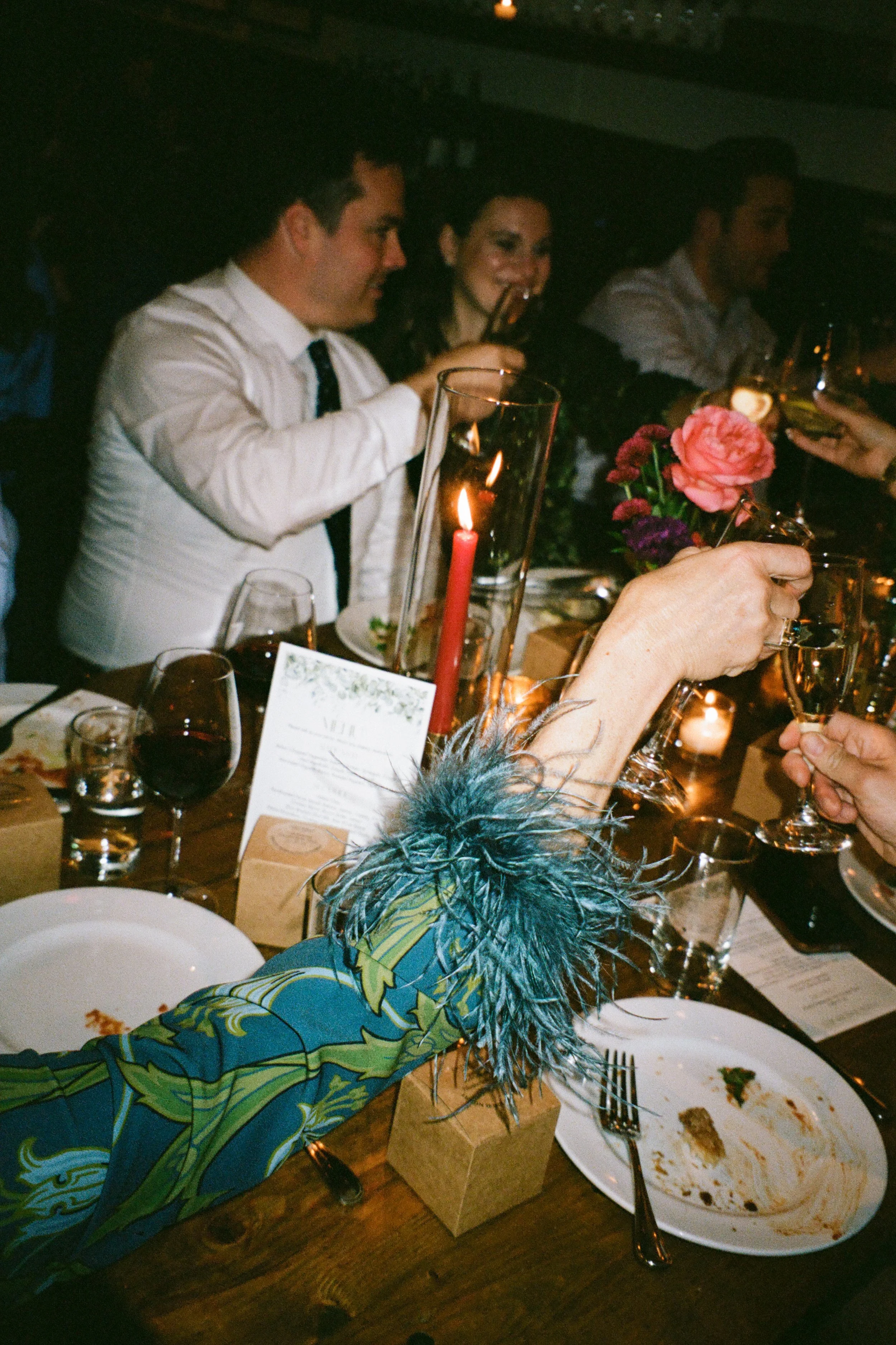 Wedding partygoers clink glasses during champagne toast at wedding at Osteria Via Stato in Chicago. Shot on film.
