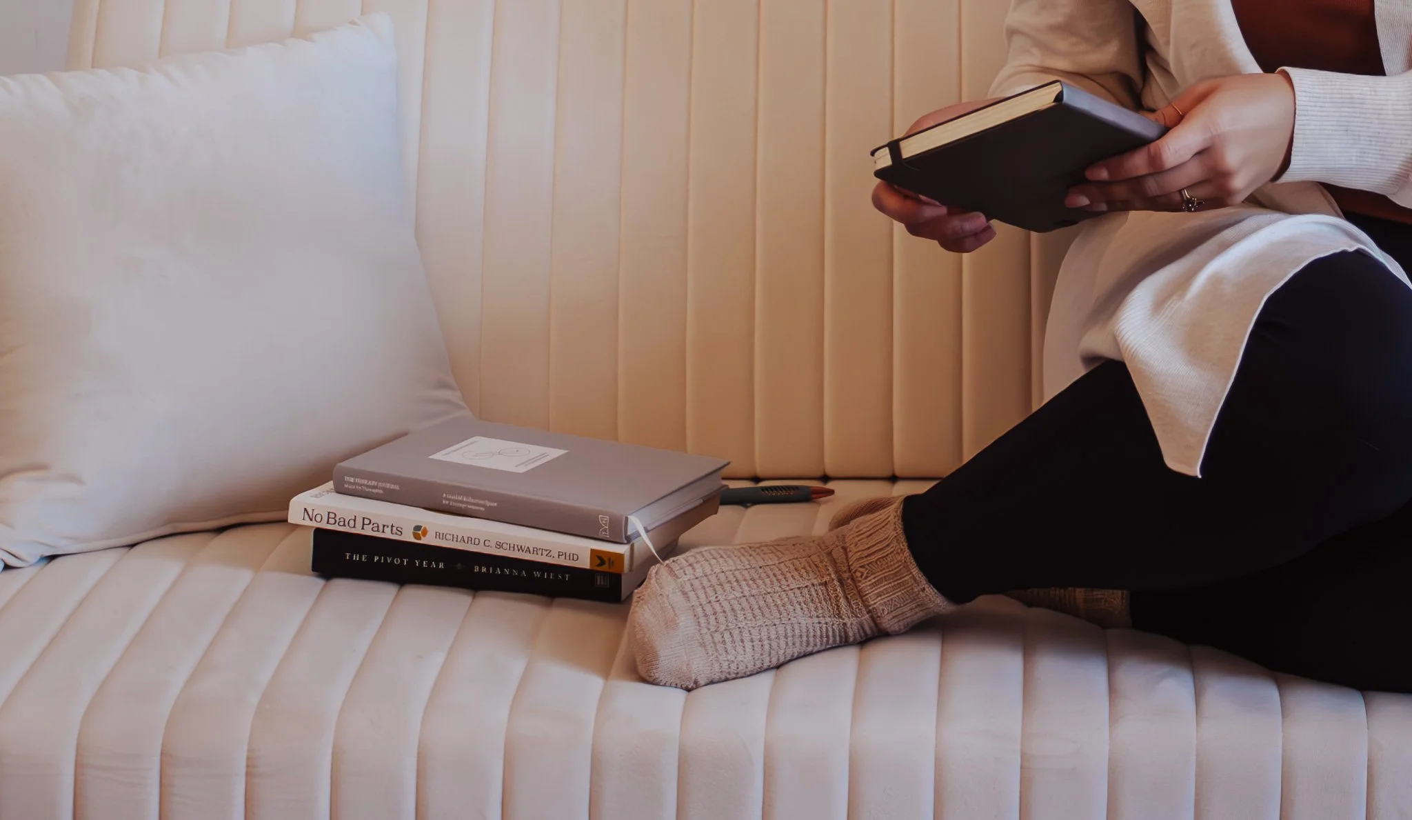 sitting on a comfortable therapy couch, therapist is cozy and reading a stack of books