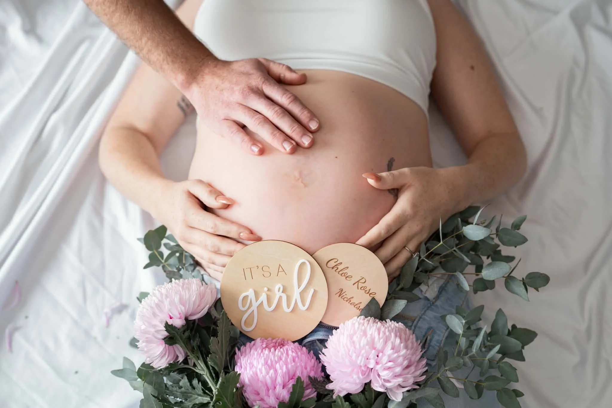 Pregnancy bump with hands holding it and flowers
