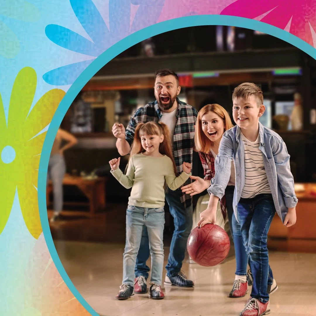 A family enjoying a game of bowling, with a young boy about to roll a bowling ball and a girl and parents cheering behind him, inside a bowling alley.