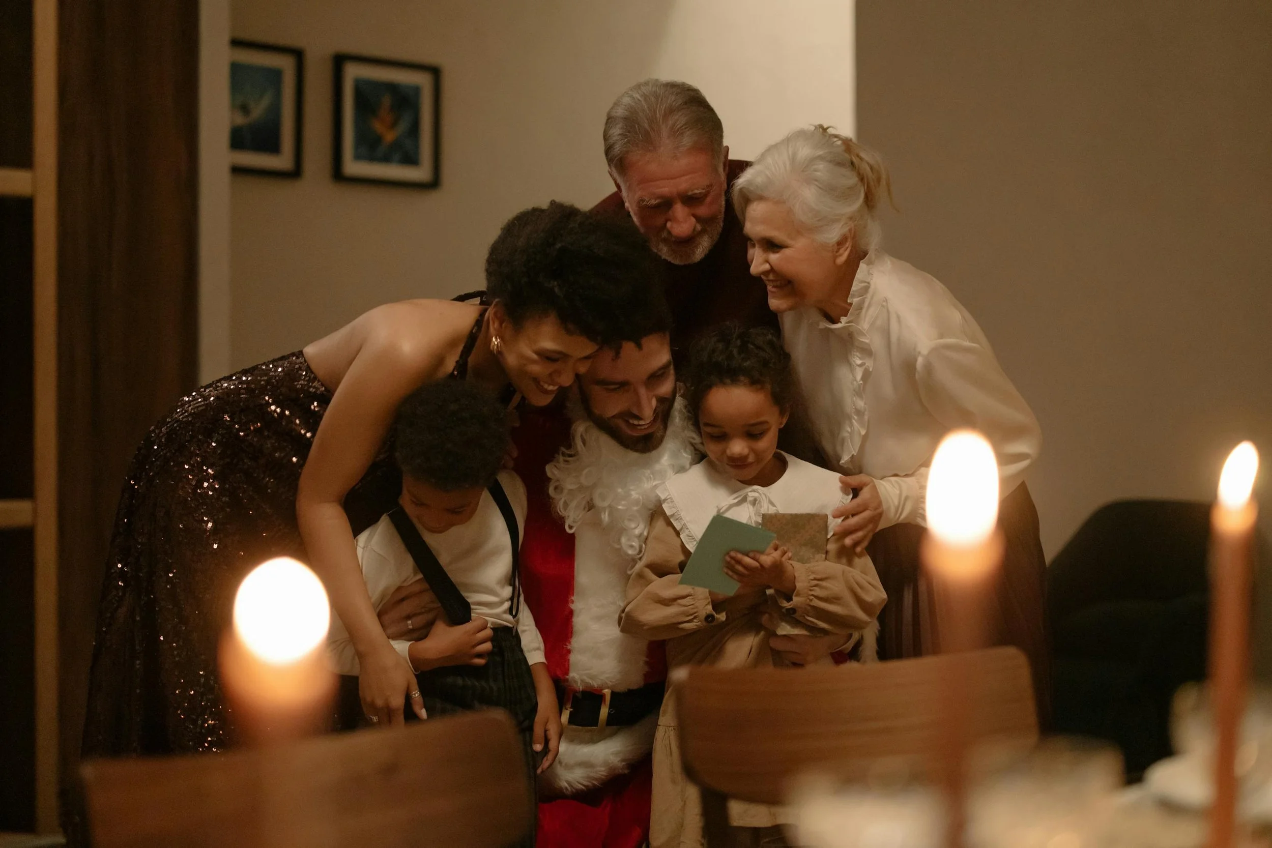 A family gathering with grandparents and candles on a table in the foreground, celebrating a holiday.