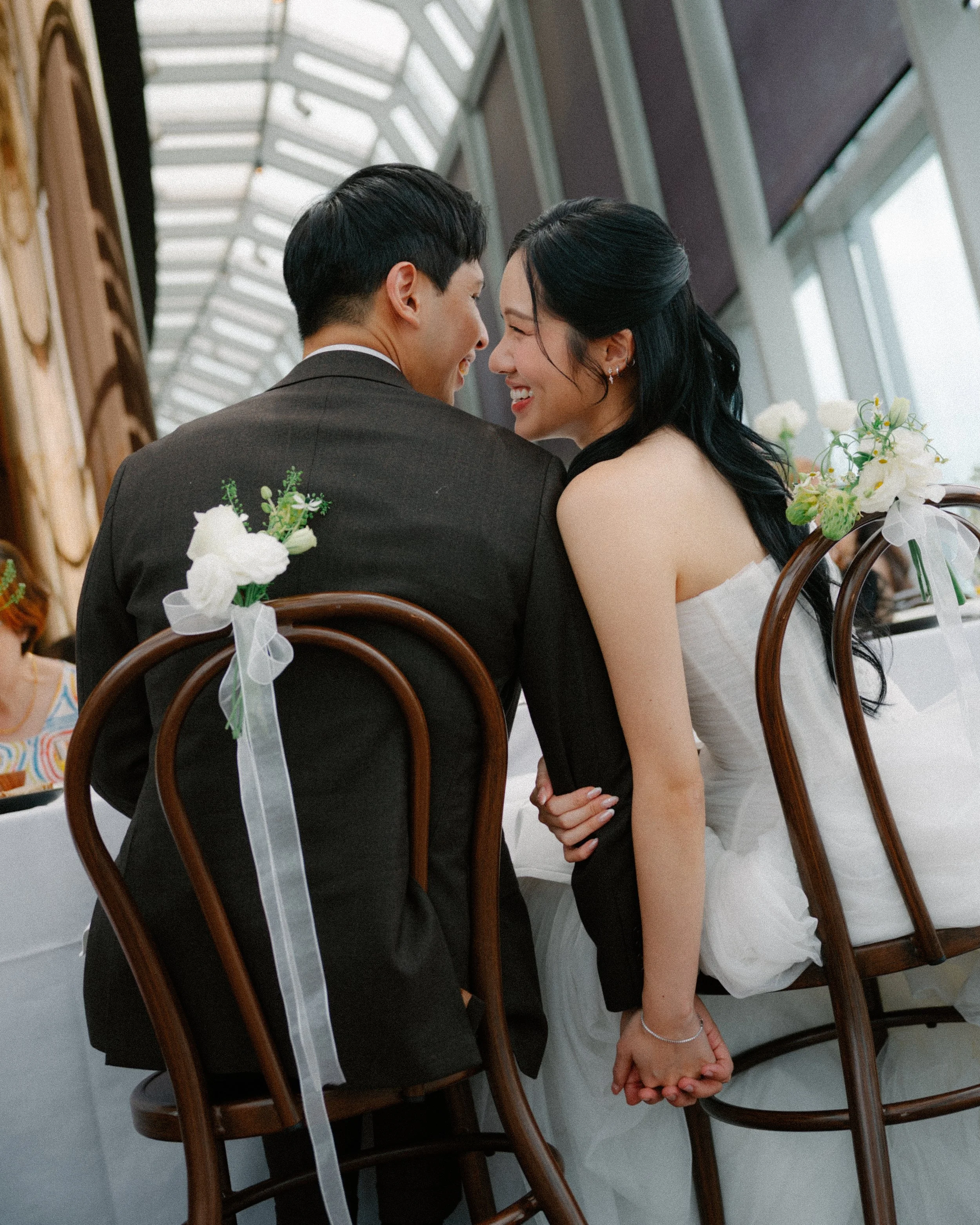 Bride and groom holding hands at reception table during emotional wedding moment at 1-Atico.