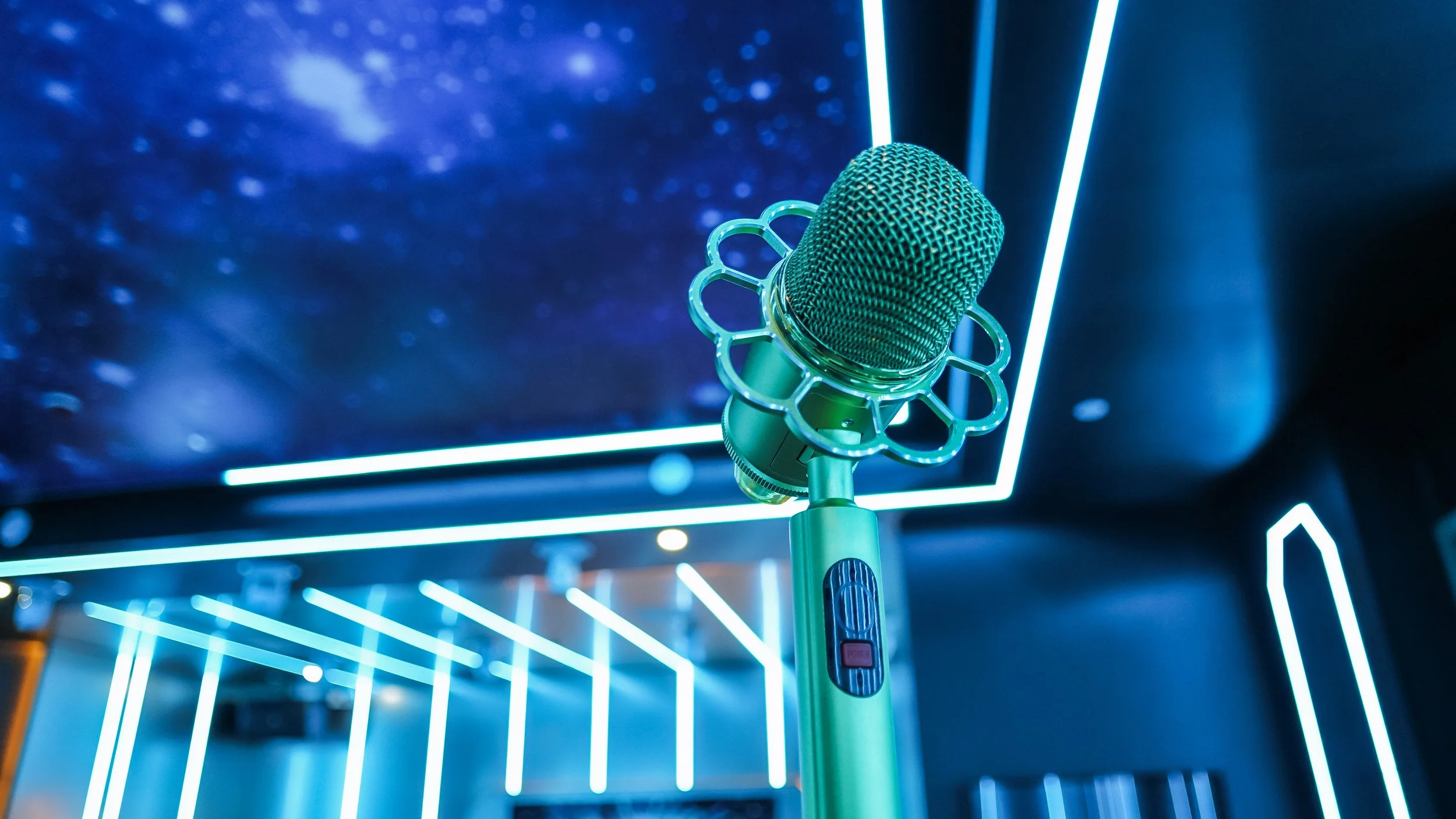 A microphone with a decorative ring around it, placed on a stand in a room with futuristic blue LED lights and dark walls.