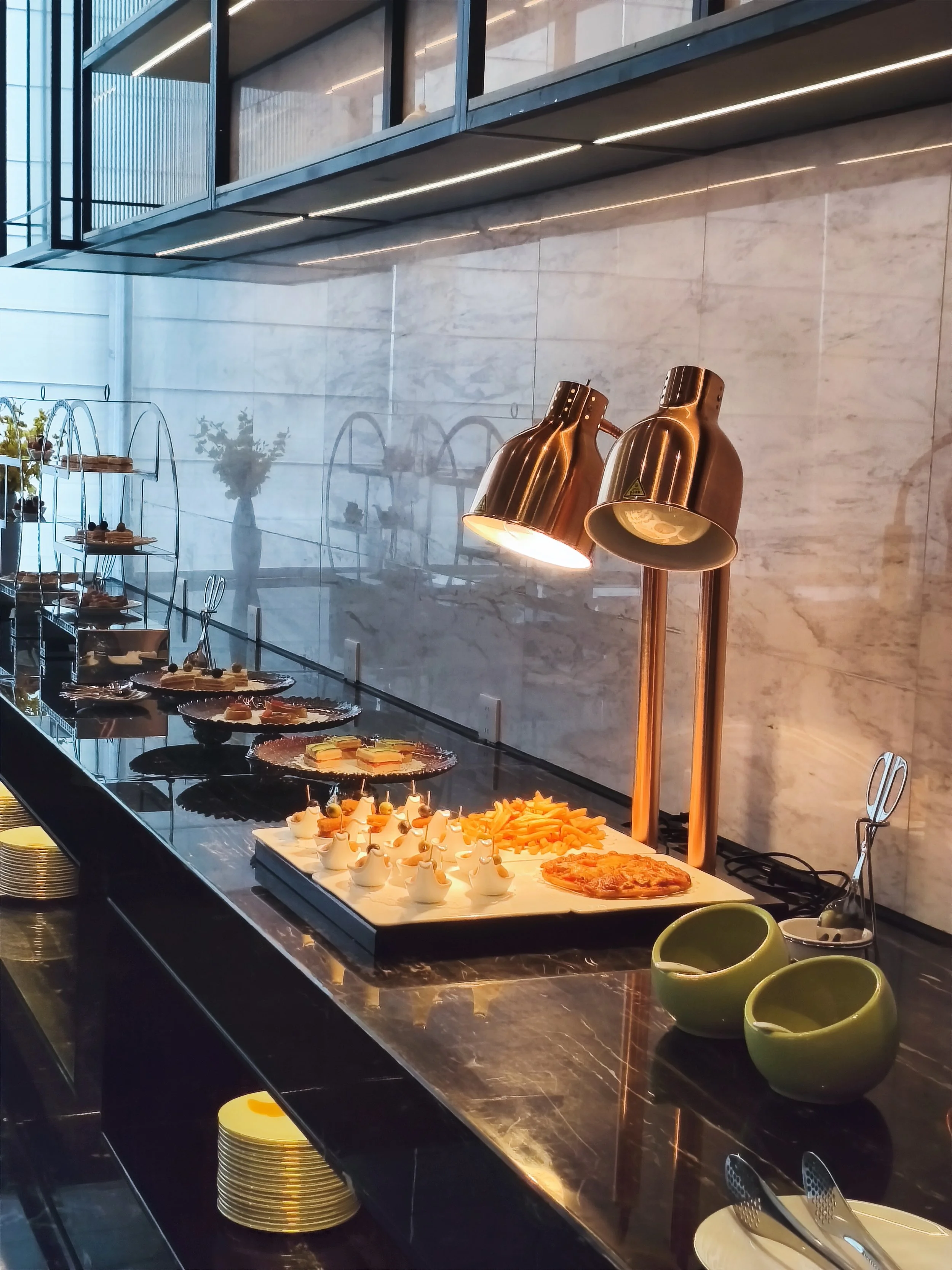 Buffet with various appetizers and snacks under warm lighting in a modern, upscale setting.