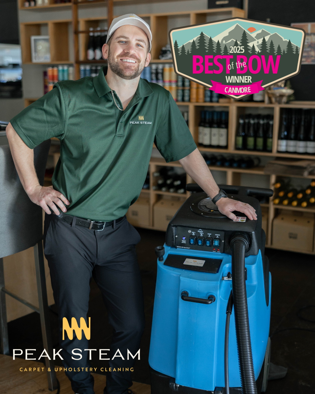A smiling man in a green Peak Steam uniform with a white cap standing next to a blue carpet cleaning machine in a store with shelves of wine bottles.