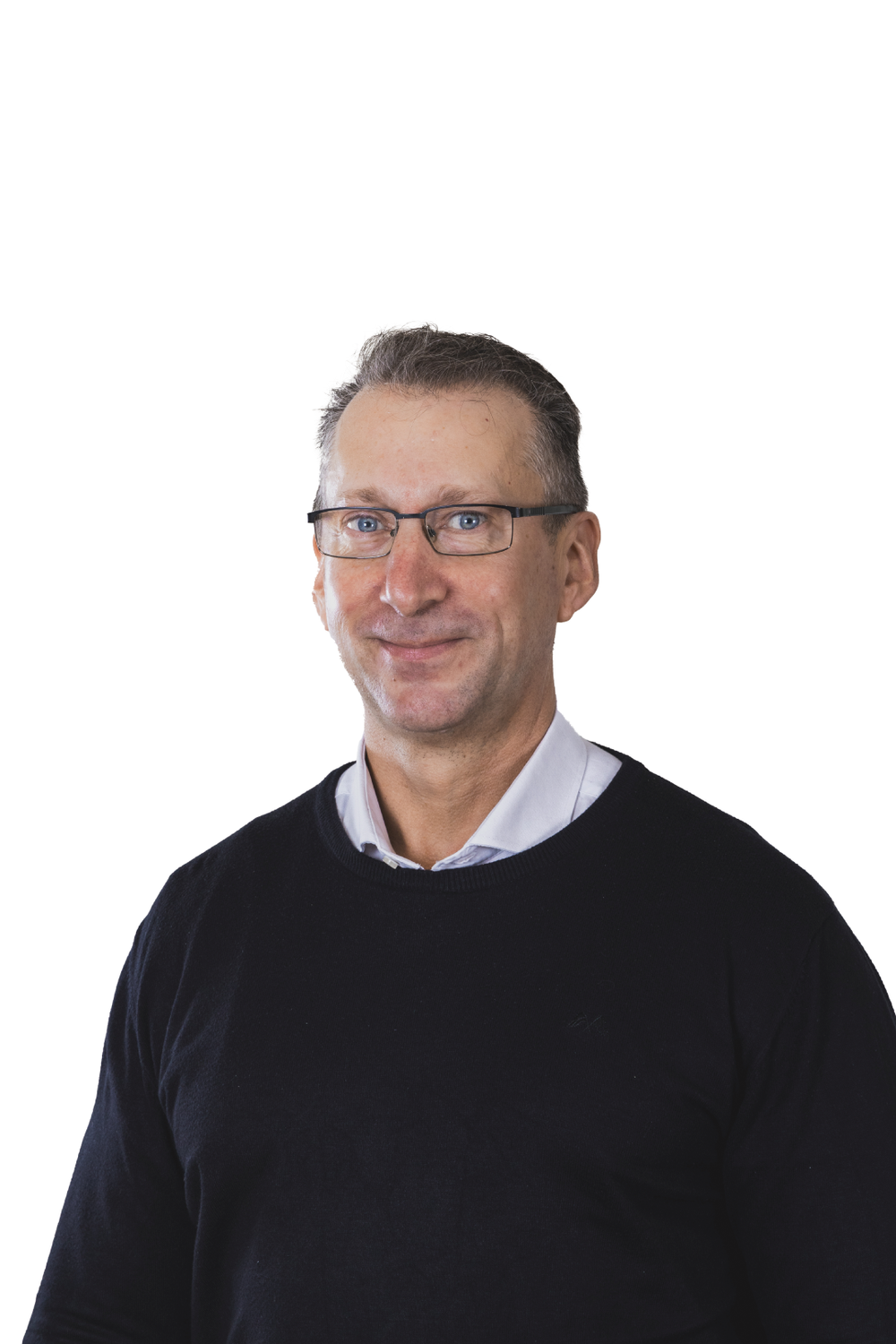 A middle-aged man with glasses, wearing a white collared shirt and a black sweater, smiling slightly against a plain white background.