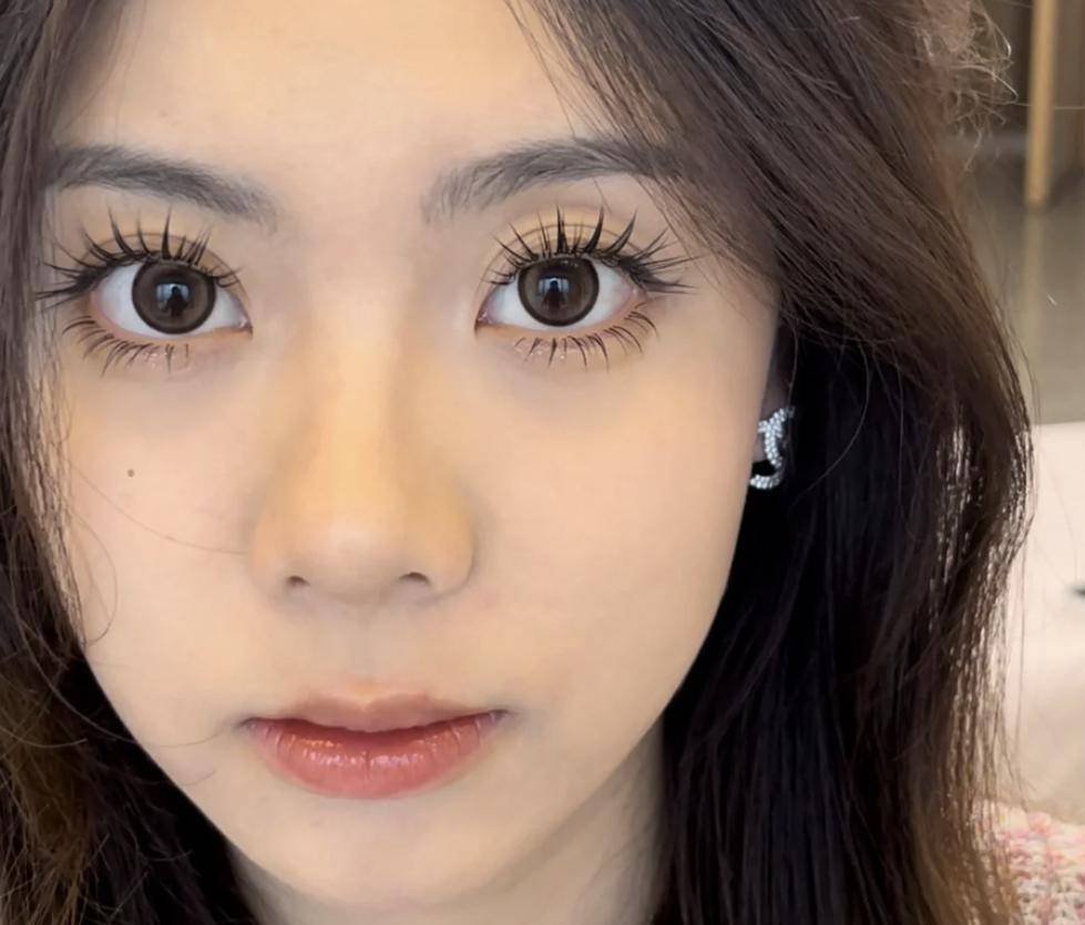 Close-up of a woman's face with large eyes, long eyelashes, and dark hair.