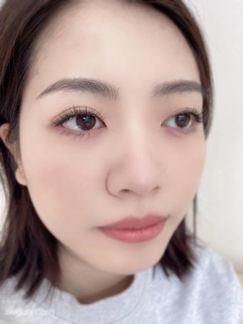 Close-up of a woman's face with natural makeup, long eyelashes, and a neutral expression.
