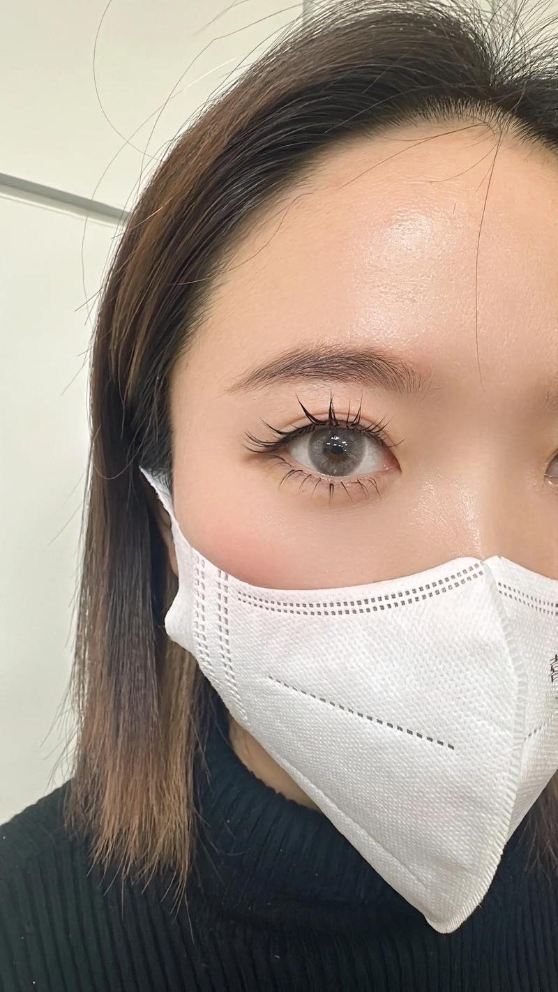 Close-up of a person wearing a white face mask, focusing on the left eye and eyebrow.