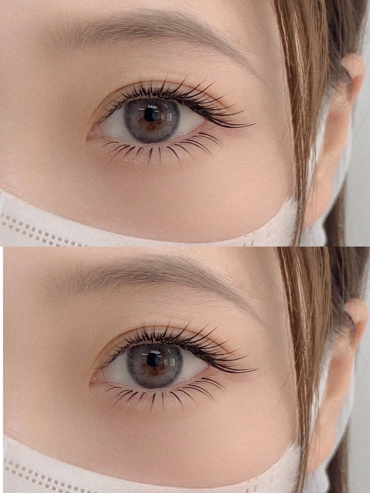 Close-up of a person's eye with gray contact lenses, long eyelashes, wearing a white face mask.
