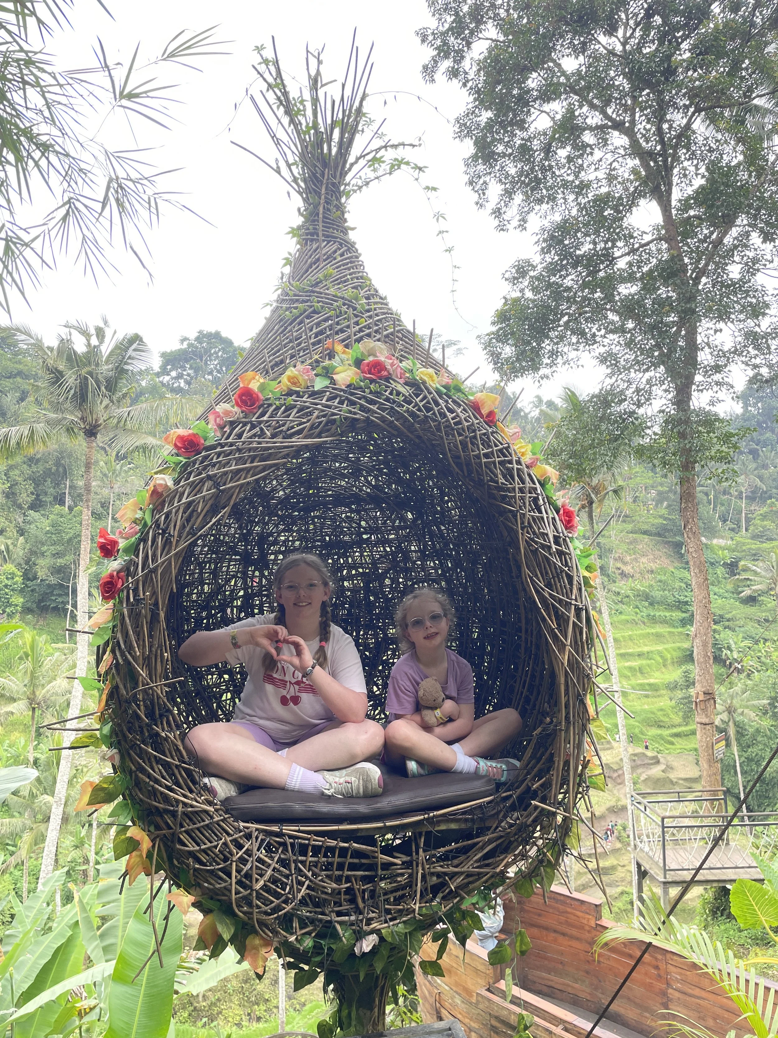 Two girls sitting inside a giant woven bird's nest photo spot in Bali
