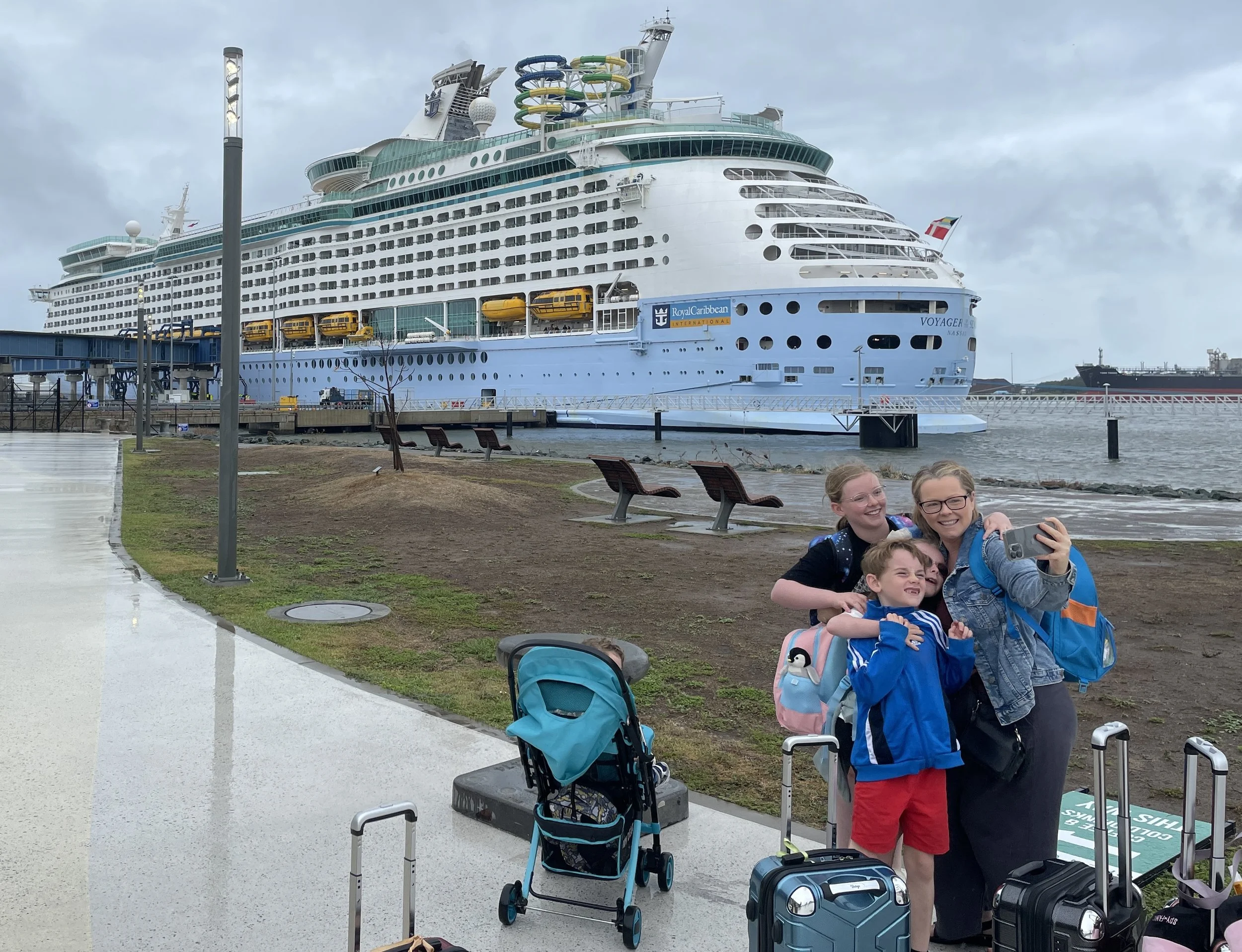 Worldschooling family with their luggage and pram at the cruise terminal in front of a Royal Caribbean ship