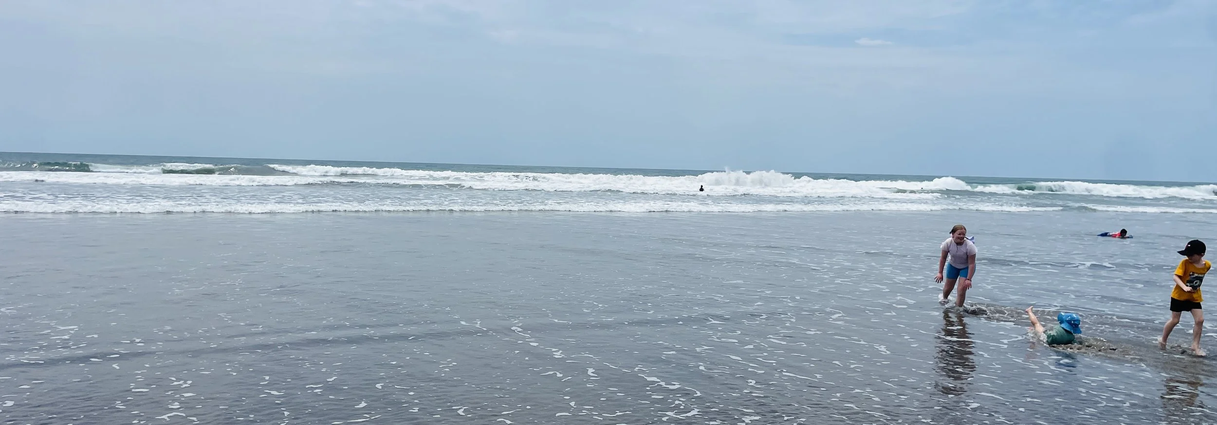 Kids playing in the shallow waves on a beach in Bali