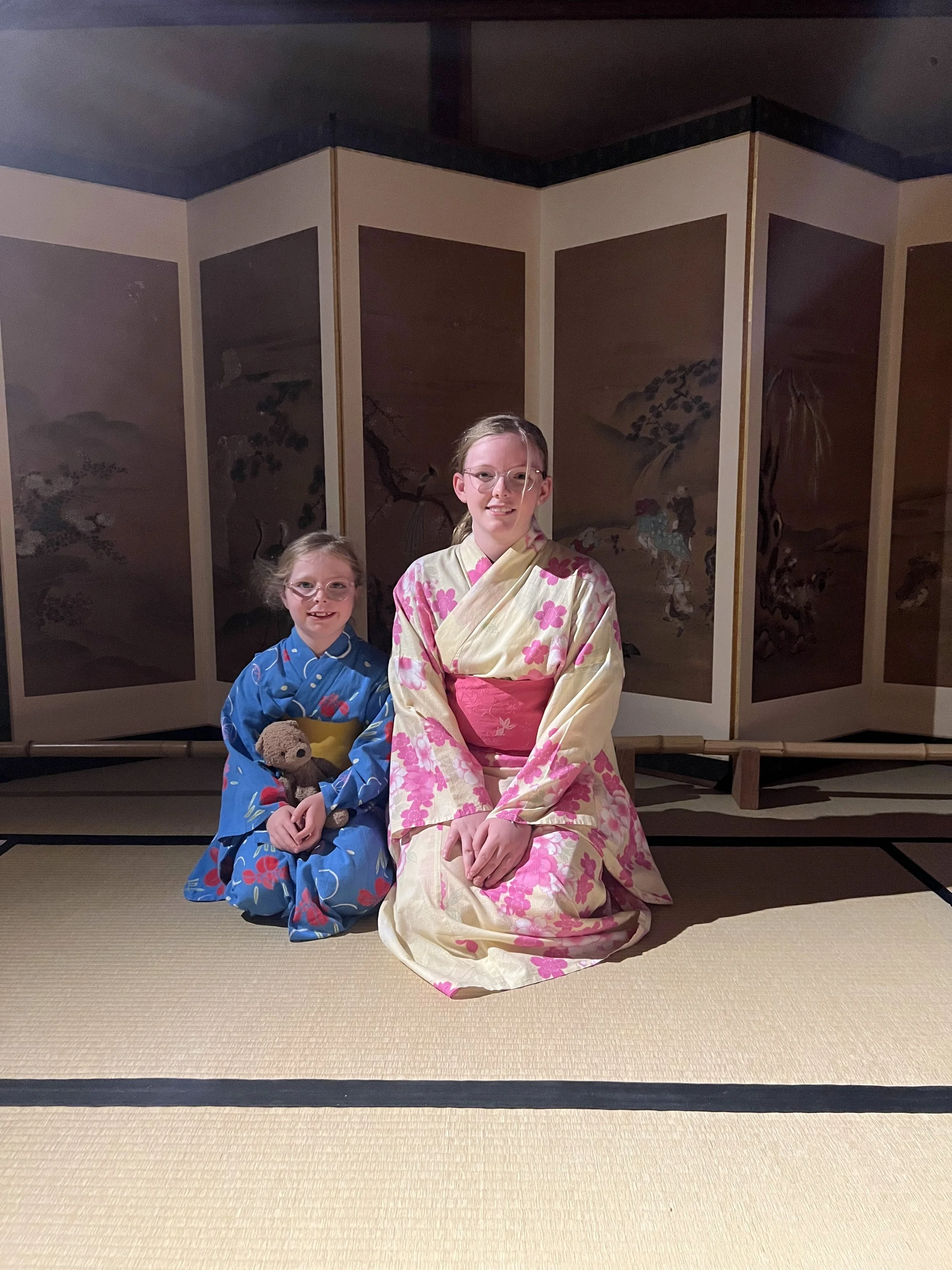 Two girls dressed in traditional kimono kneeling in a tatami room in Japan